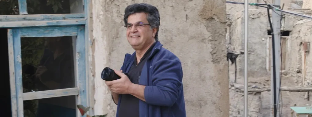 Jafar Panahi con cámara retrato cineasta iraní en entorno urbano