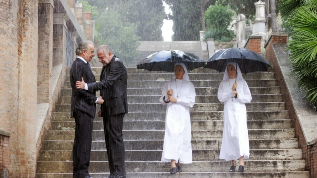 Fotograma de una película de Paolo Sorrentino con varios personajes bajo la lluvia en una escalinata.