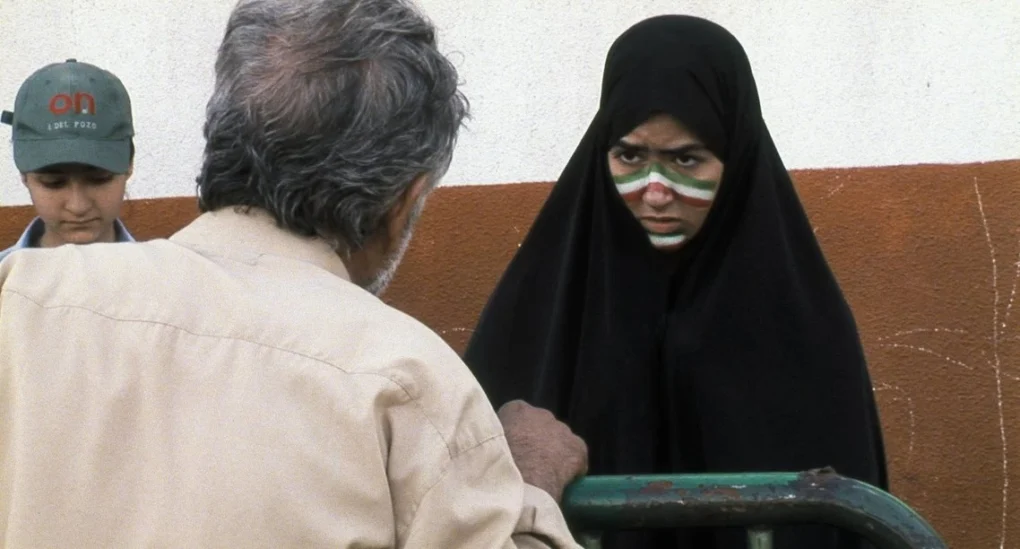 Fotograma de Offside (Fuera de juego) de Jafar Panahi con una joven aficionada retenida frente a un hombre junto al estadio.
