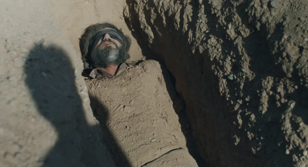 Hombre con los ojos vendados semienterrado en una zanja en Un simple accidente (2025), de Jafar Panahi