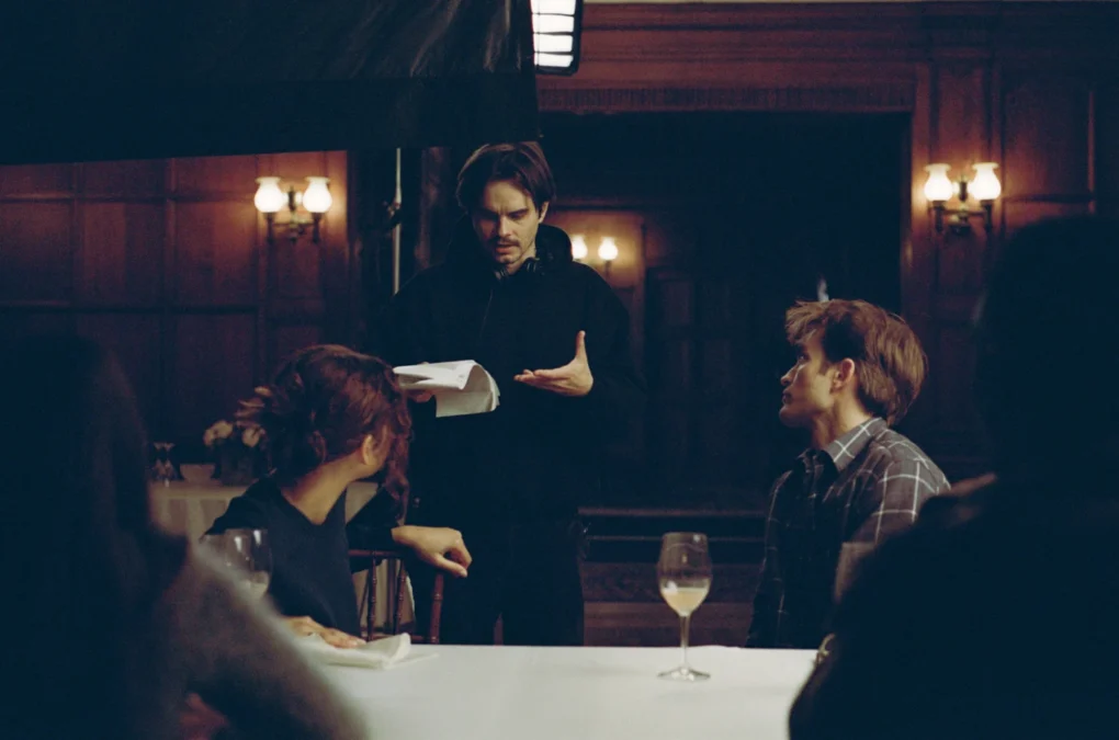 Personaje de pie durante una cena de confesiones en The Drama (2026)